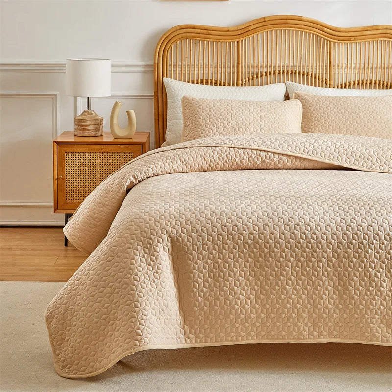 A beige plaid queen bedspread set featuring a quilted cover and matching pillow shams on a wooden bed frame.