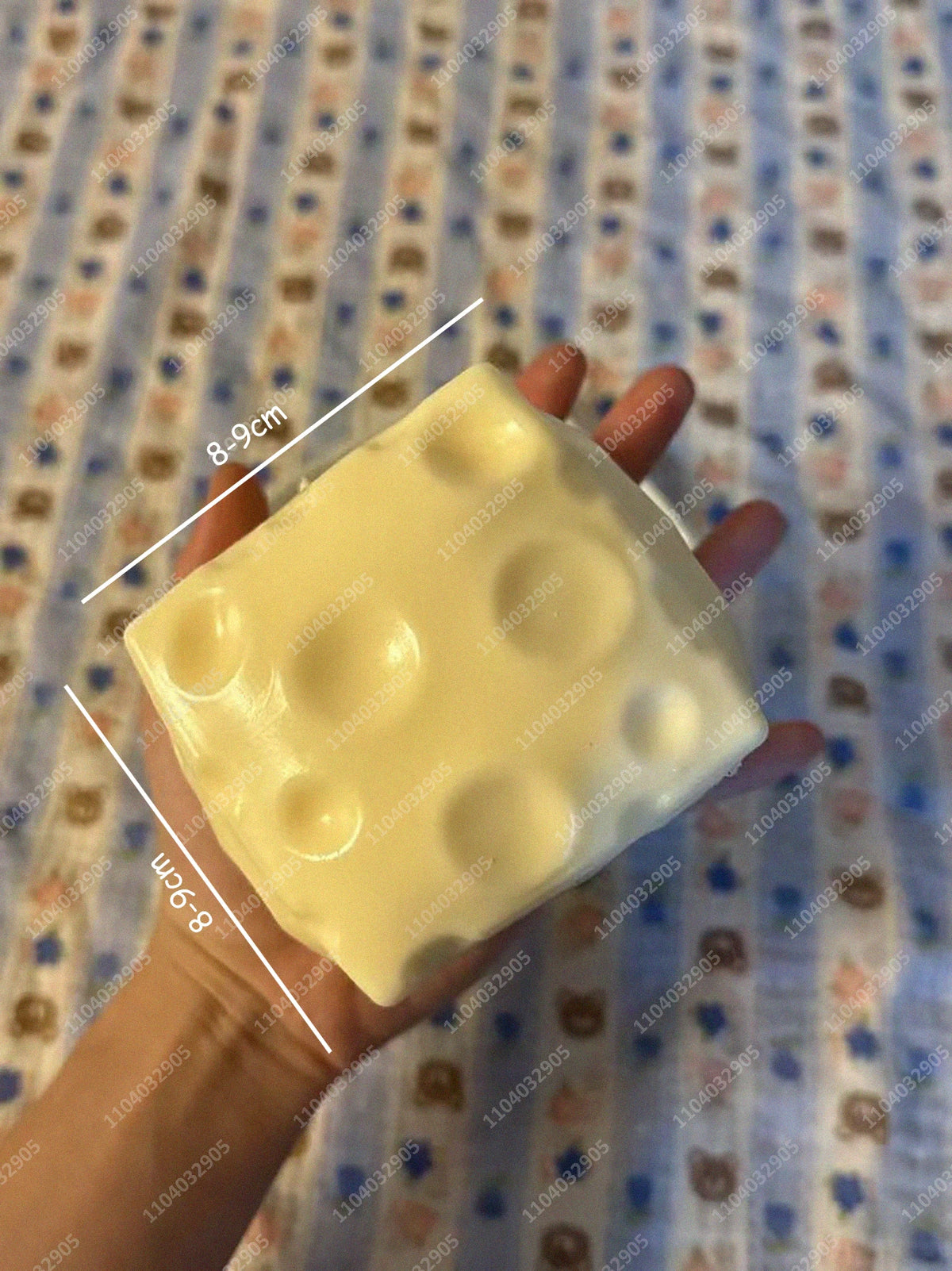 Eine Hand hält einen großen, blassgelben, weichen Stressball mit Maßen von 8,9 cm by 8 cm.