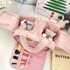 A pink travel makeup bag with a wide opening is shown open, revealing cosmetic products and a skincare item.