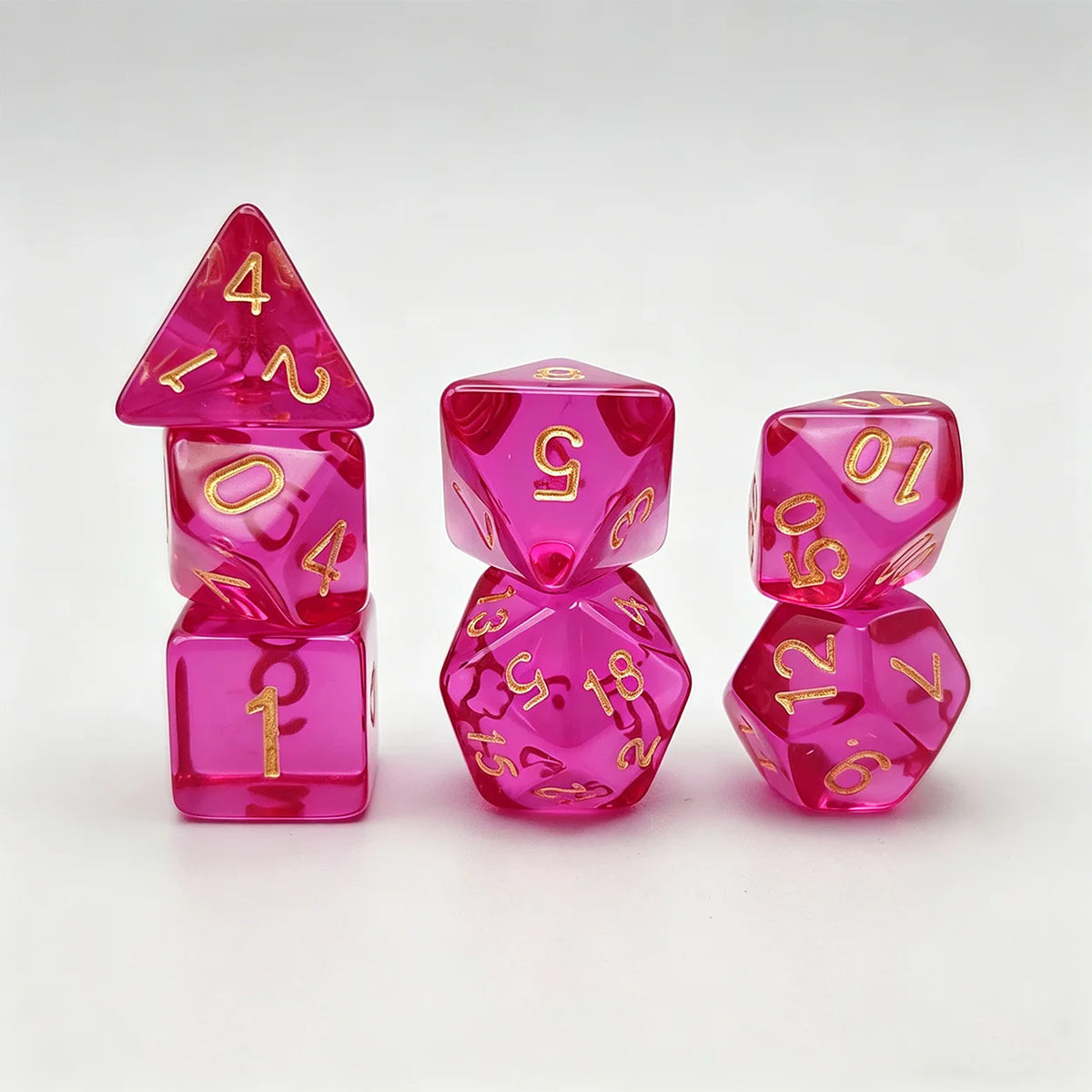 A set of seven translucent pink acrylic polyhedral dice, including a tetrahedron and several dodecahedral dice.