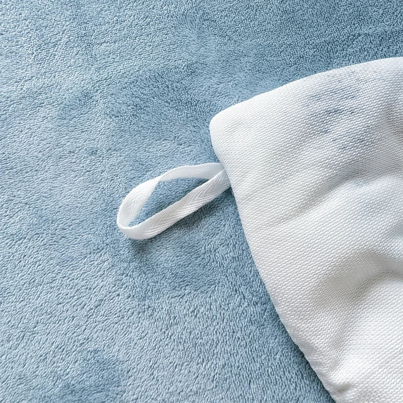 White plush fleece duvet cover with a rabbit design lying on a blue fabric surface.