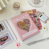 A pink mini photo album titled Collect with a heart design next to a heart check book and a small light gray device.