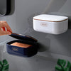 A hand is holding an open blue soap holder, next to a closed white version of the two-tier draining soap holder.