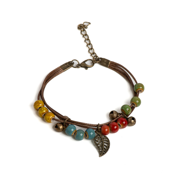 Adjustable ceramic bead bracelet with wooden cord and leaf pendant featuring various colored beads.
