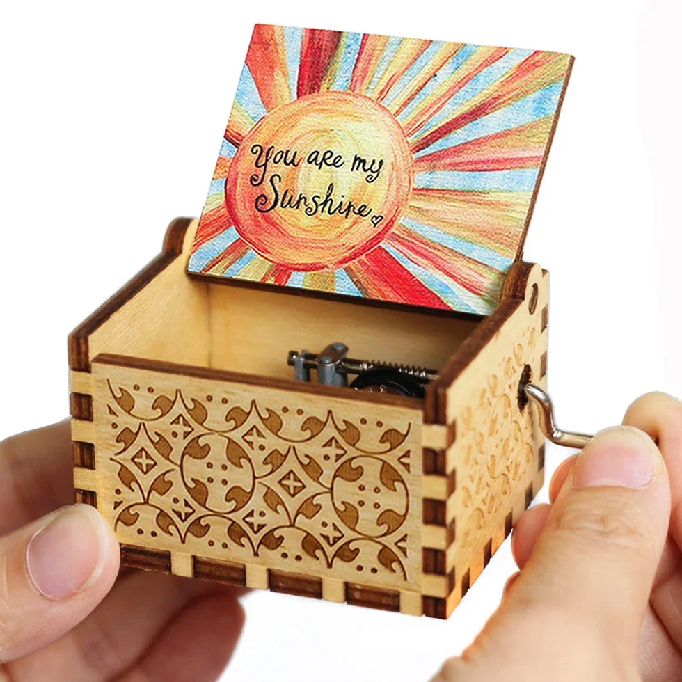 A wooden music box with a hand-crank mechanism and a card featuring the text You Are My Sunshine