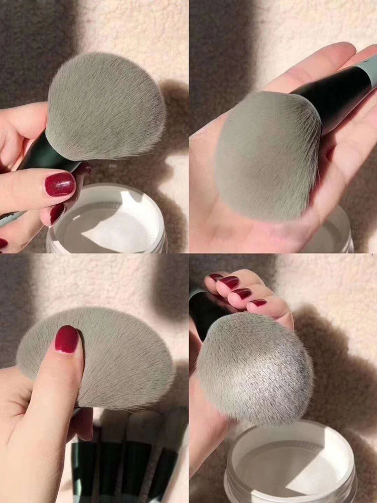A set of 13 makeup brushes in a gray color being held and displayed against a light background.