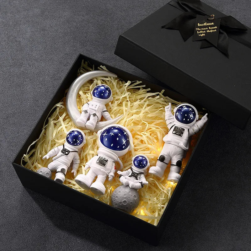 A set of five handcrafted astronaut figurine resin spaceman desk decor figures displayed in a black box.