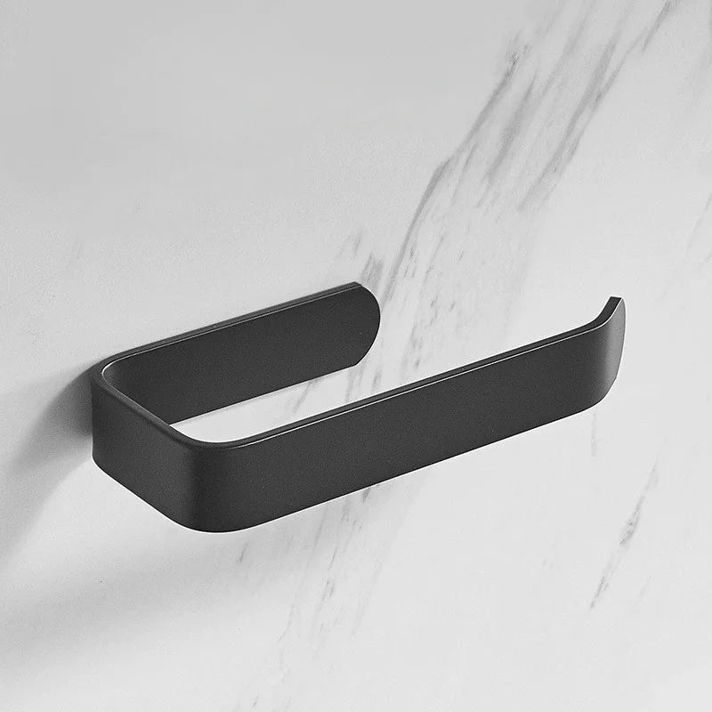 A matte black no-drill self-adhesive toilet paper holder mounted on a white marble wall.