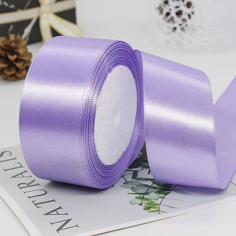 A roll of purple satin ribbon used for gift wrapping or DIY crafts, shown next to a piece of paper.