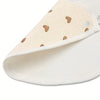 A close-up view of a cream-colored baby cotton gauze bib with small brown heart embroidery and a waterproof backing.