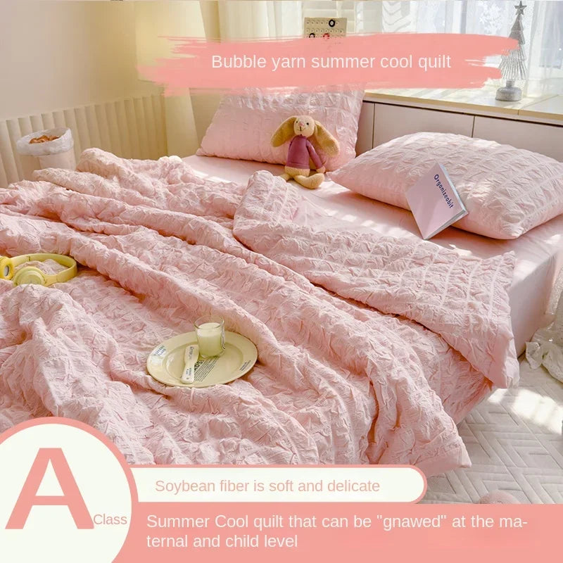 Pink bubble yarn summer cool quilt with a stuffed animal and a plate on the bed