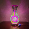A handcrafted Turkish mosaic table lamp with a vibrant pink and yellow glass base and multicolored mosaic pattern, glowing wa