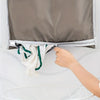 A hand opens a gray wall-mounted laundry storage bag to reveal white towels inside.