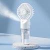 A white portable USB rechargeable mist fan with a perforated grille and a clear hydration bottle is displayed on a light surf