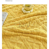 A yellow jacquard taffeta fabric blanket with a textured weave is displayed on a surface, emphasizing gentle care and tempera