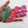 Three translucent silicone glitter squishy toys in shades of teal, pink, and purple held in a hand.