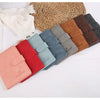 Collection de porte-passeports en cuir colorés dans des tons de rose, rouge, bleu, vert, marron et noir, posés sur un tissé