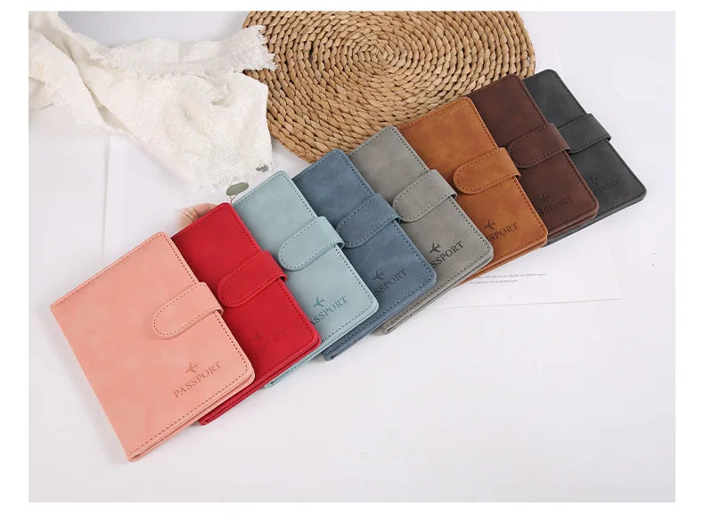 Collection de porte-passeports en cuir colorés dans des tons de rose, rouge, bleu, vert, marron et noir, posés sur un tissé