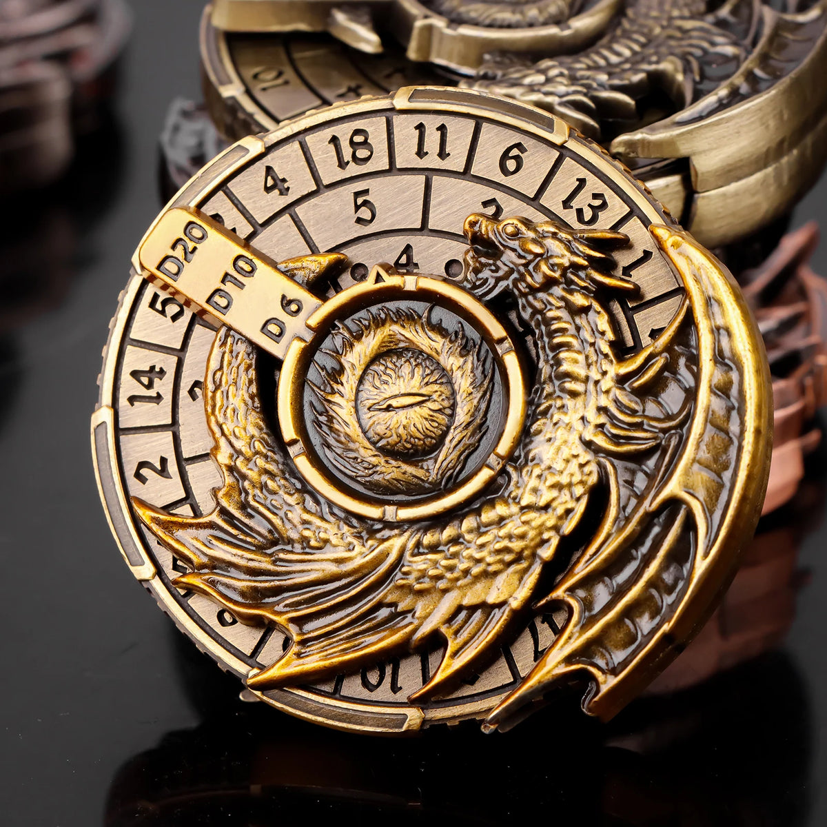 A close-up of a brass metal spinner dice cube with numbered faces and an embossed dragon design.