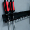 A black wall-mounted tool organizer with red and black handles for holding various tools.
