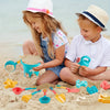 A young girl and boy play with an 18-piece beach and sand toy set featuring various shovels and tools on the sand.