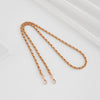 A close-up of a gold-toned metal chain strap with adjustable buckles, laid diagonally on a white surface.