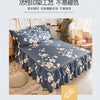 Une jupe de lit bleu marine à imprimé floral blanc, avec des bords froncés, est exposée sur un lit.