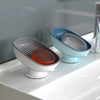 A set of suction cup soap holders in light blue and gray are displayed on a white countertop.