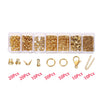 Assortment of gold-colored jewelry findings including jump rings, clasps, and crimps packaged in small plastic compartments.
