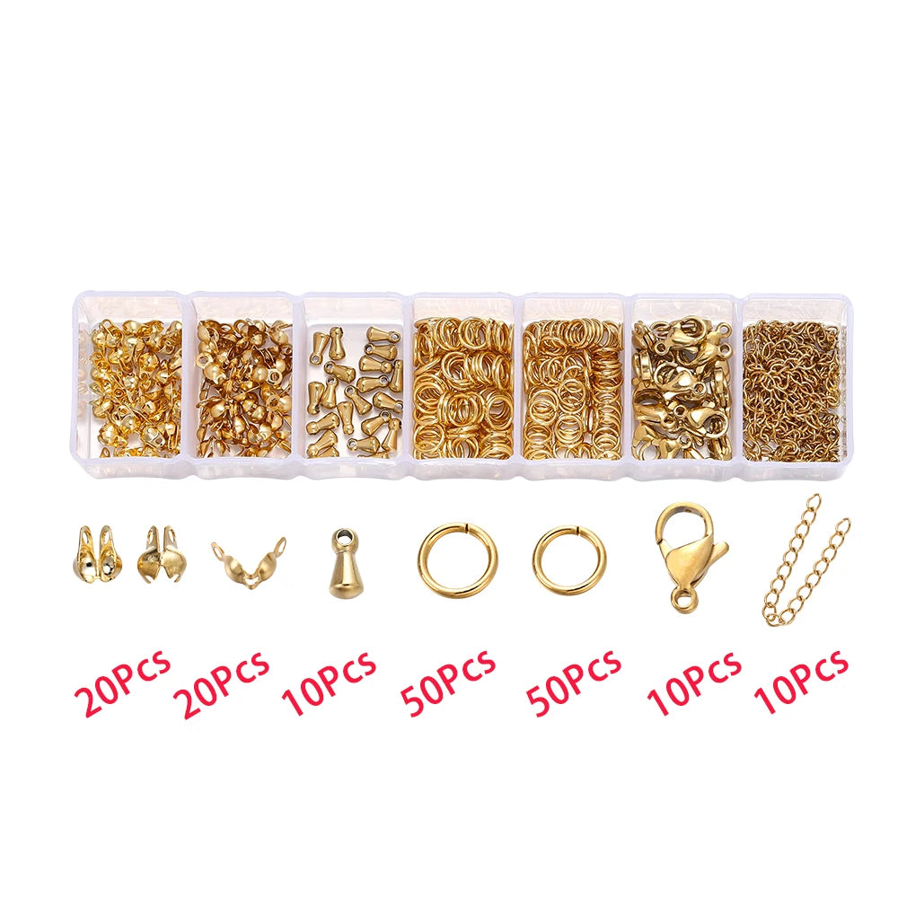Assortment of gold-colored jewelry findings including jump rings, clasps, and crimps packaged in small plastic compartments.