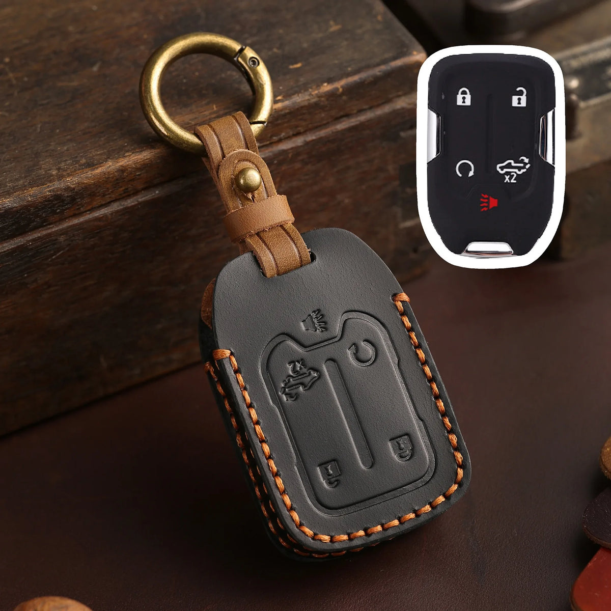 A dark brown leather key fob case with a brass ring attached, shown next to a white electronic key fob.