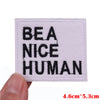 A square white embroidered patch with black text reading BEANICE HUMAN