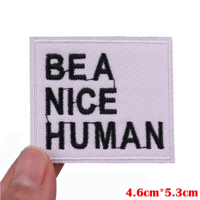 A square white embroidered patch with black text reading BEANICE HUMAN