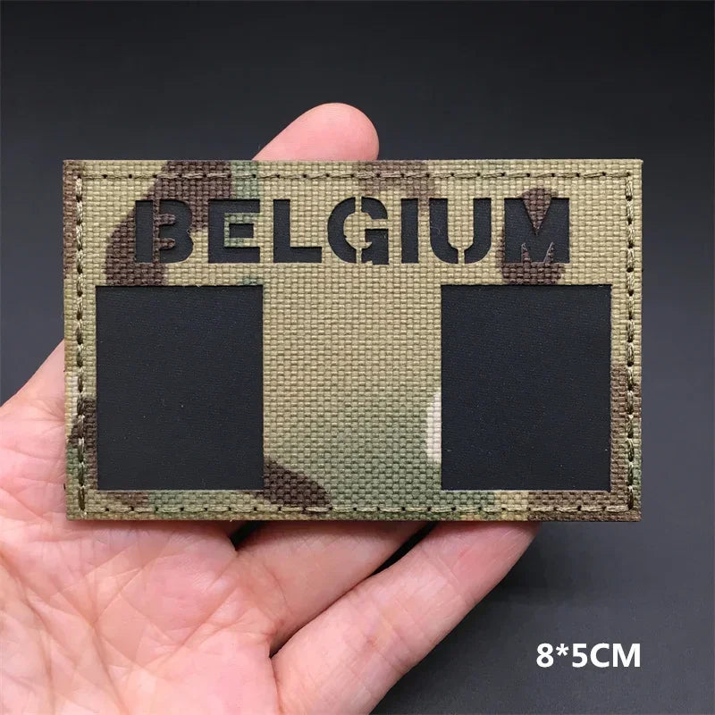 A close-up of a Belgium national flag tactical patch with hook-and-loop backing and camouflage pattern.