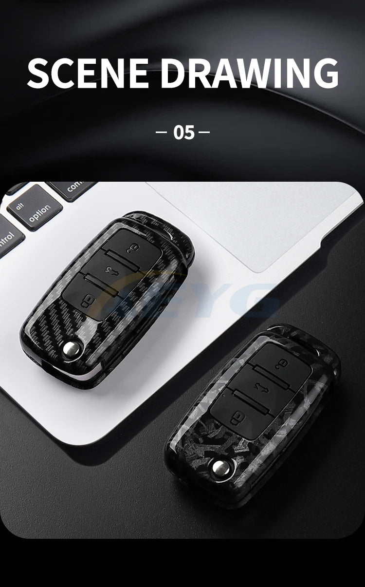 Close-up view of a black carbon fiber car key cover resting on a white laptop keyboard.