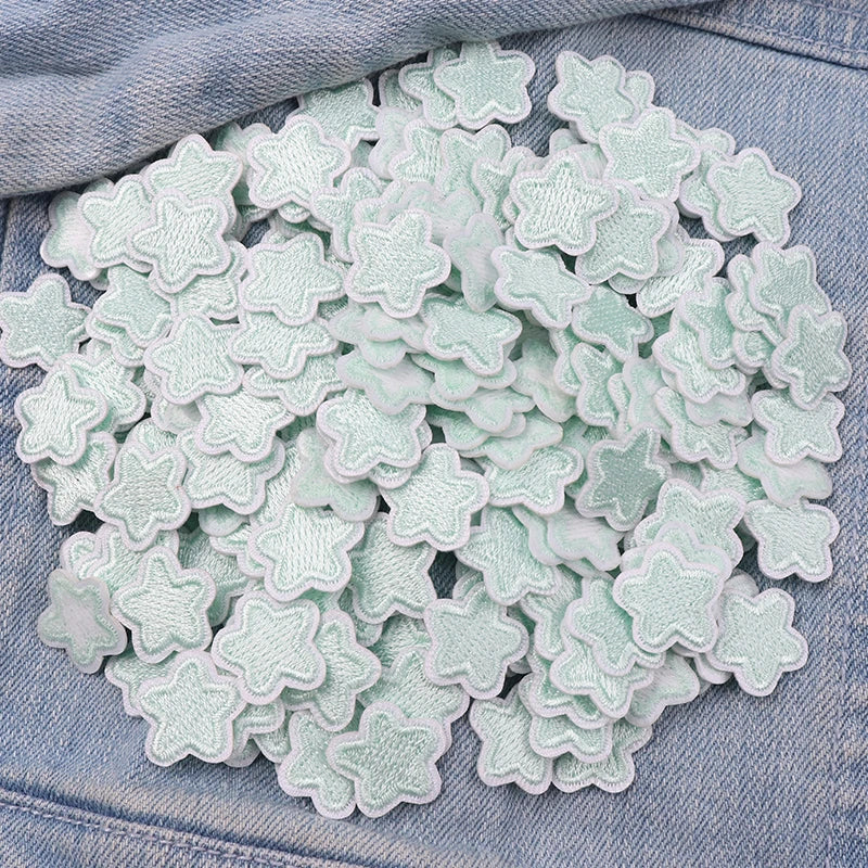 A pile of light mint green embroidered star-shaped iron-on patches for DIY clothing decoration