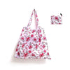 A pink floral patterned reusable shopping tote bag with an attached carry pouch.