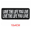 Black embroidered iron-on letter patch with white text that reads Love the life you live live the life you love