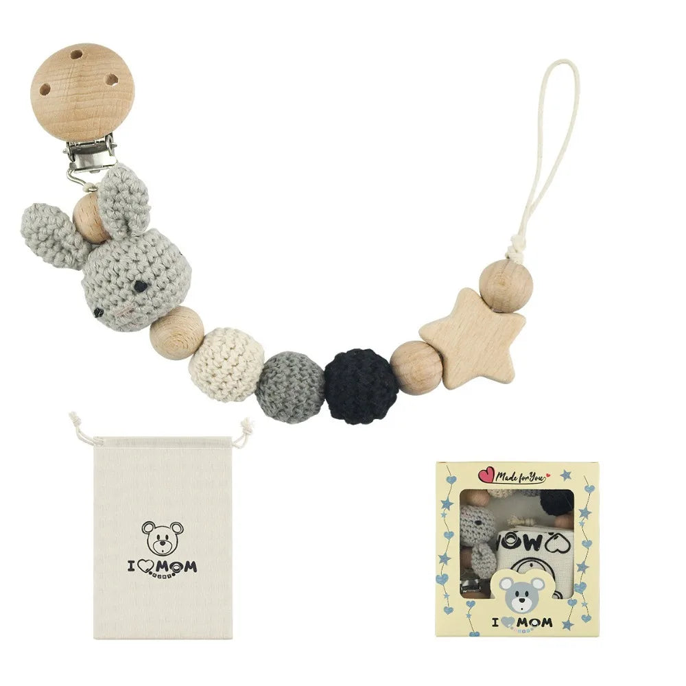 A wooden pacifier clip chain made of crochet beads in natural wood and gray colors, with a small pouch and card.
