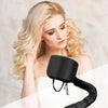 A woman is holding a black reusable hair drying and conditioning cap against her shoulder.