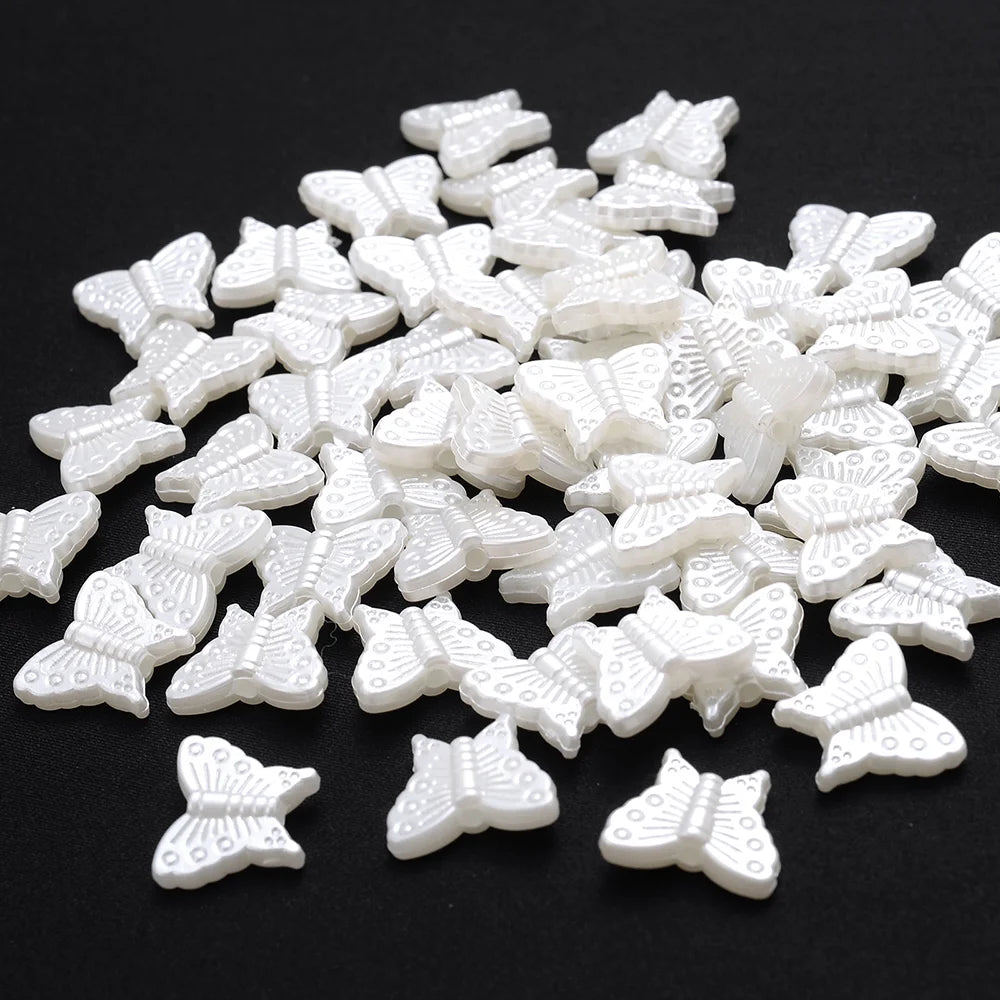 A pile of 100 white acrylic pearl spacer beads shaped like butterflies.