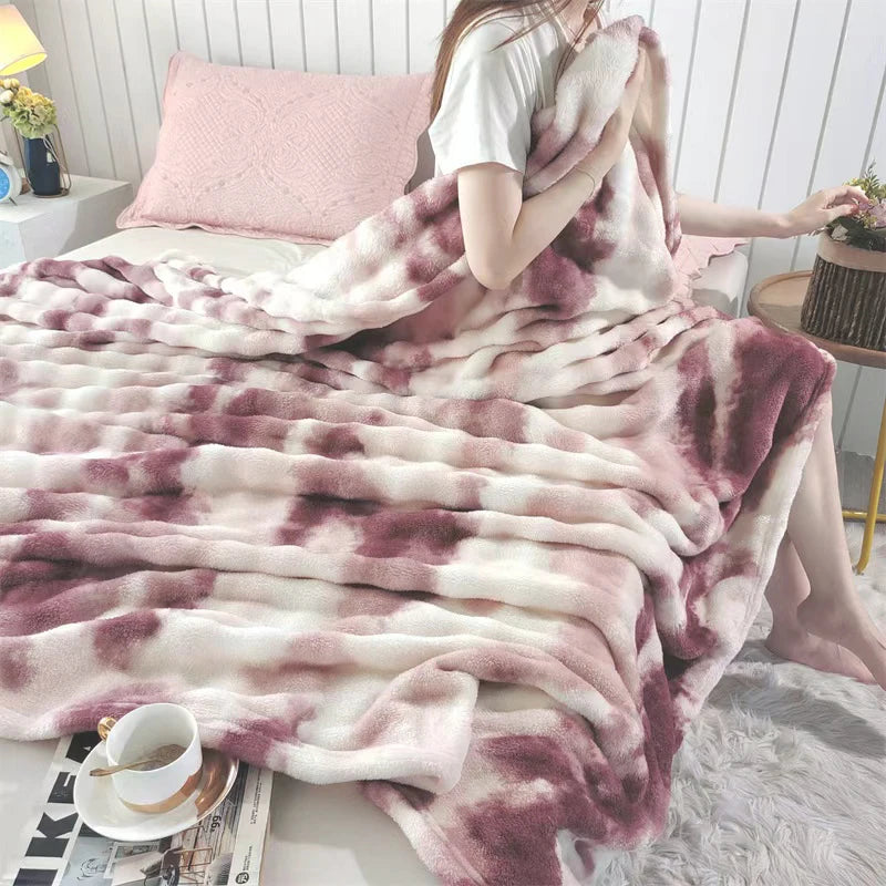 A pink and purple gradient bubble fleece throw blanket draped over a person on a bed.