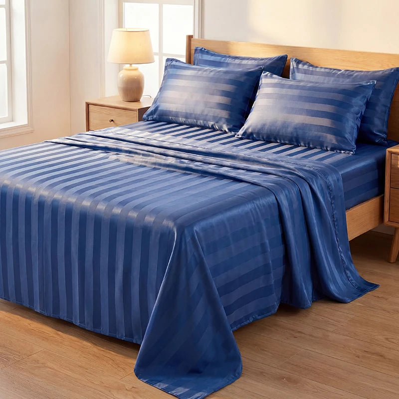 A blue striped satin bed sheet set with matching pillows is displayed on a wooden bed frame.