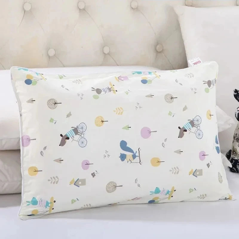 A white cartoon patterned pillowcase with various animal and nature motifs resting on a white surface.