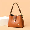A brown leather shoulder bag with a gold-toned strap resting on a light background.