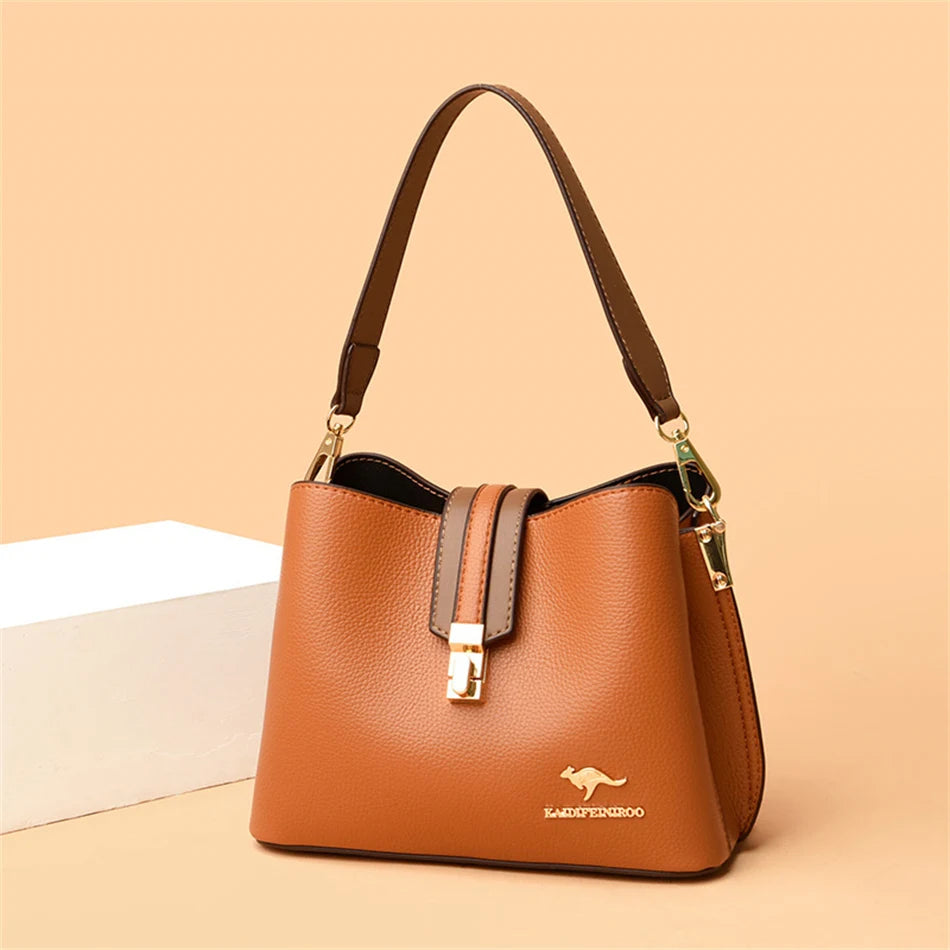 A brown leather shoulder bag with a gold-toned strap resting on a light background.