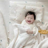 A baby is wrapped in a white coral fleece blanket with bear embroidery.