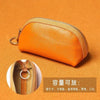 Orange PU leather key organizer wallet with zipper shown against an orange background.