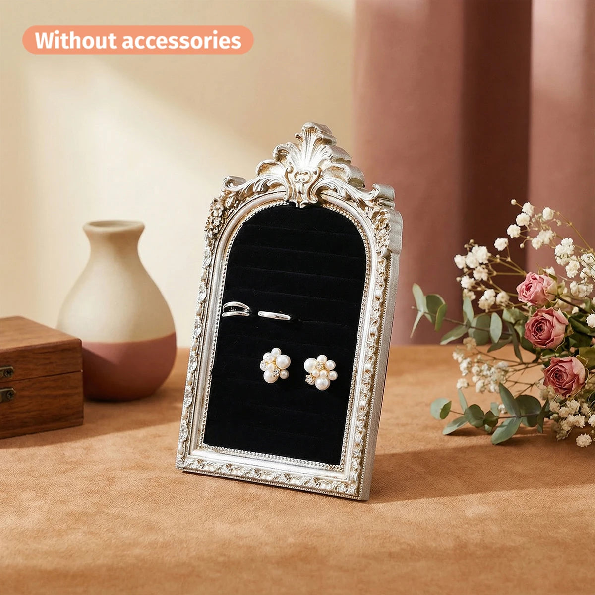 Silver arched resin jewelry display stand with floral design featuring pearl earrings on a brown surface.