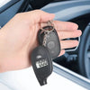 A hand holds a black digital tire pressure gauge with an LCD display and metal keyring.